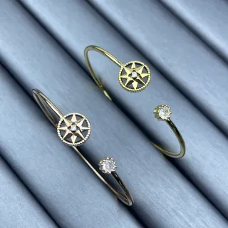 Bracelates de tono dorado con rosa de compás y cristal solitario de puño abierto