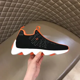 Tênis lifestyle pretos e laranjas de malha com sola de onda na parte do meio e fechamento slip-on