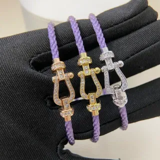 Pulsera de cordón trenzado morado y dorado con broche en forma de lira