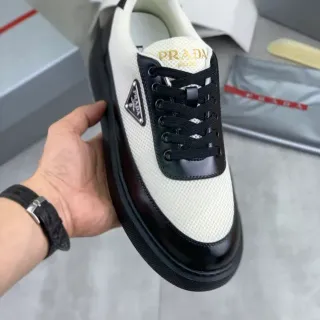 Prada Sneakers Lifestyle Blanc Noir Panneaux Maille et Cuir Verni Plaque Logo Métal Triangulaire