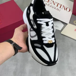 Valentino Rockstud negro y blanco, paneles de malla y ante, hardware dorado VLogo, chunky sneakers