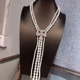 Collier blanc argenté à multiples rangs de perles orné de cristaux avec fermoir papillon