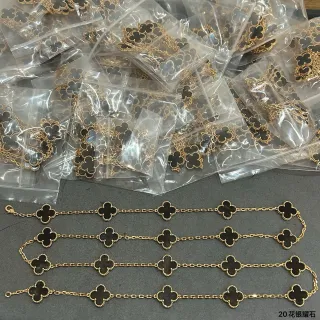 Pulsera con cadena de oro y negro y colgantes en forma de trébol